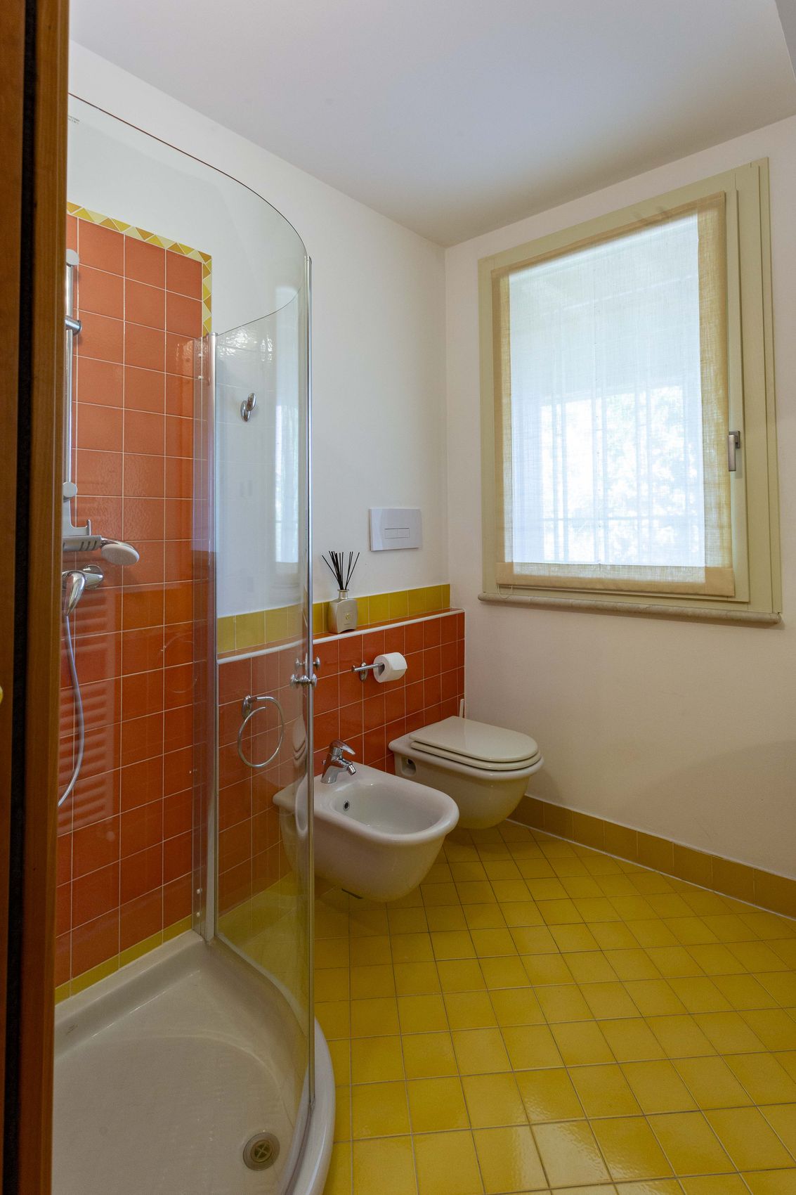 The orange bathroom used by the fourth room