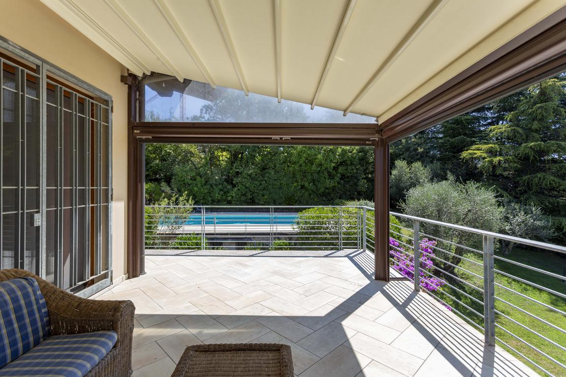The covered loggia with wicker sofas, looking out to the pool